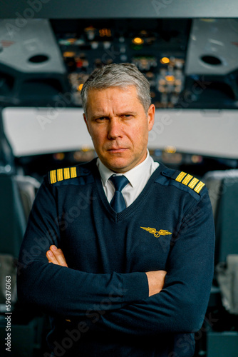 Portrait of serious airplane captain in uniform preparing for flight in aero simulator cockpit