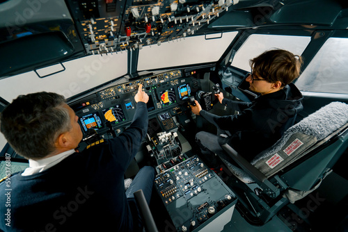 An experienced pilot instructs a young student before a training flight in the cockpit of an aero simulator photo