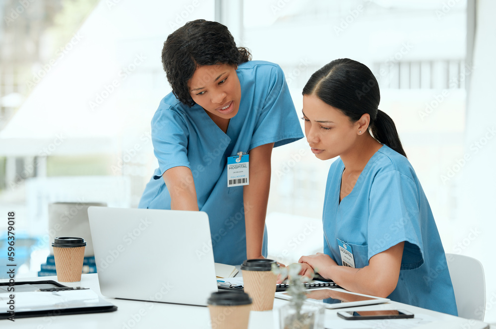 Lets do some research. Shot of two young female doctors using a laptop at a hospital. Lets do some research. Shot of two young female doctors using a laptop at a hospital.