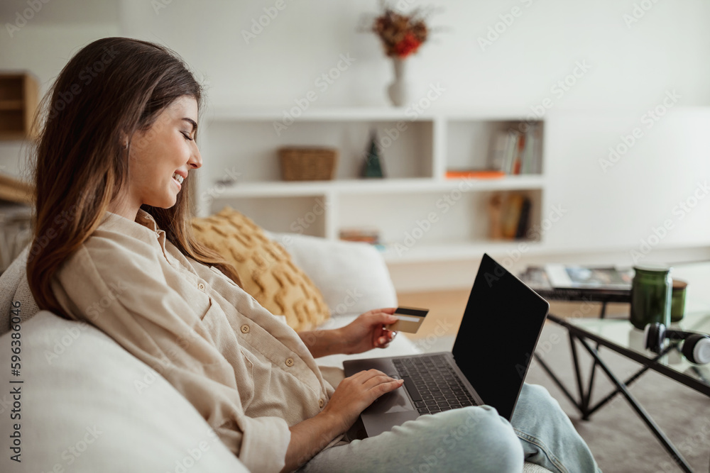 Positive millennial european female typing on computer, use credit card, enjoy online shopping Positive millennial european female typing on computer, use credit card, enjoy online shopping