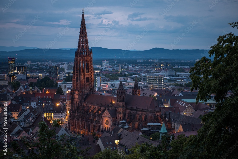 Blick auf die Stadt Freiburg (Deutschland) von oben bei Sonnenuntergang und aufziehendem Gewitter über den Vogesen