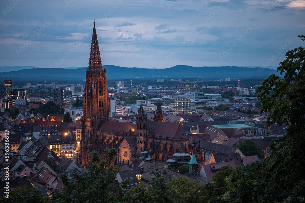 Blick auf die Stadt Freiburg (Deutschland) von oben bei Sonnenuntergang und aufziehendem Gewitter über den Vogesen