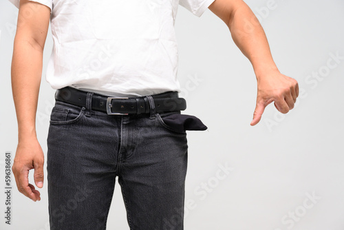 Black jean man turning his empty pockets inside out isolated on white background.Man turning out the jean pocket to showing no money.Bankrupt, bad economy, loss and no money concept. © arcyto