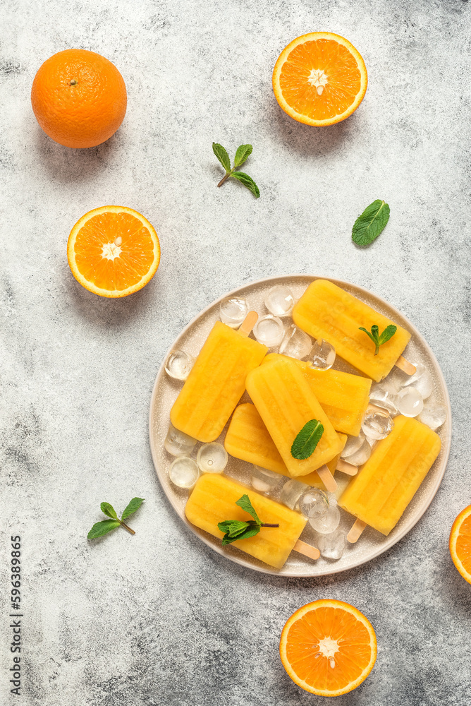 Orange popsicles , light gray stone background. Top view, flat lay, copy space. Frozen orange juice on a stick. Orange popsicles , light gray stone background. Top view, flat lay, copy space. Frozen orange juice on a stick.