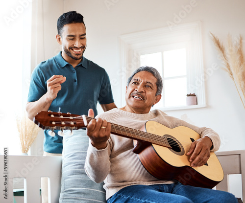 Nothing sweeter than the sound a guitar makes. Shot of a young man listening to his father play the guitar at home.