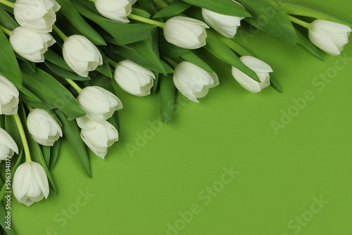 Beautiful bouquet of white tulip flowers with card on green background, space for text #596394077