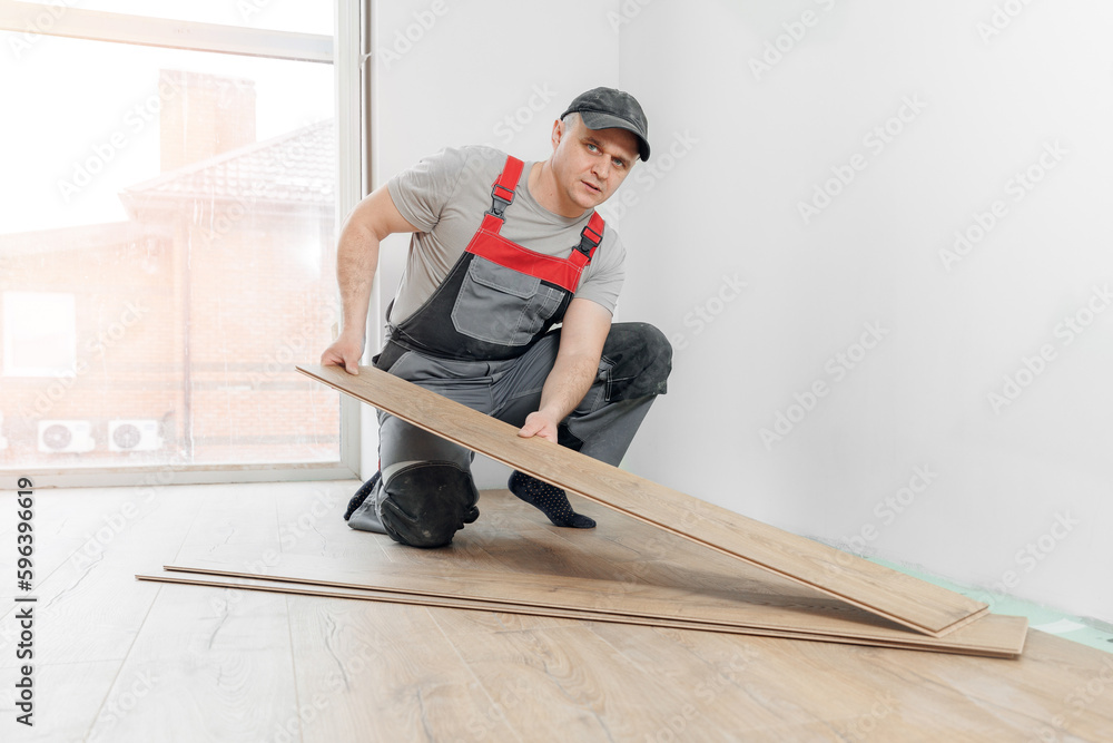 Professional builder Installing laminate flooring at home, sun light Professional builder Installing laminate flooring at home, sun light