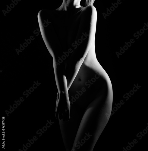 Naked woman silhouette in the dark. A beautiful girl with a naked body. Black and white portrait