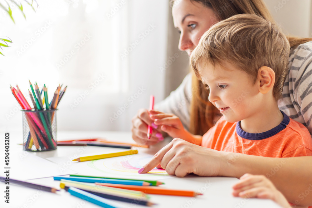 Mother and child drawing with pencils sitting at the desk at home Mother and child drawing with pencils sitting at the desk at home