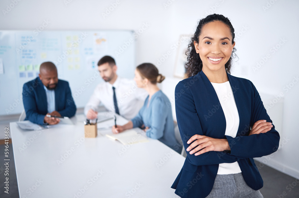 Portrait of confident smiling mixed race businesswoman leaning on desk in boardroom with arms folded. Diverse group of businesspeople in meeting and working behind happy hispanic manager in an office Portrait of confident smiling mixed race businesswoman leaning on desk in boardroom with arms folded. Diverse group of businesspeople in meeting and working behind happy hispanic manager in an office