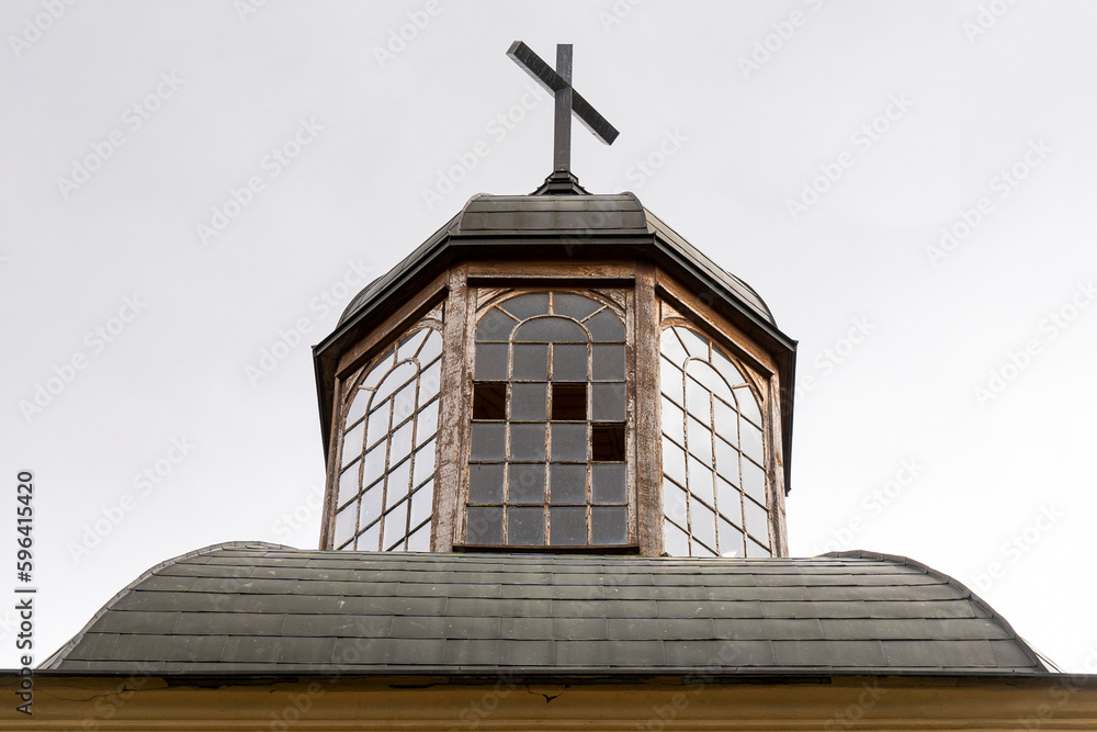 Old church tower with broken windows and with a cross on top
