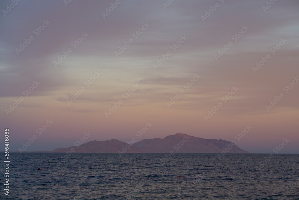 Robinson Crusoe island with rocks. Lone island, sunset light. Tropical remote island in the ocean. Sunset with sea and Tiran island view in Sharm El Sheikh, Egypt.