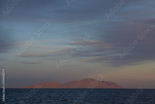 Robinson Crusoe island with rocks. Lone island, sunset light. Tropical remote island in the ocean. Sunset with sea and Tiran island view in Sharm El Sheikh, Egypt.