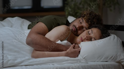 Young middle eastern couple in love sleeping in bed and hugging, man embracing his wife late in night, tracking shot
