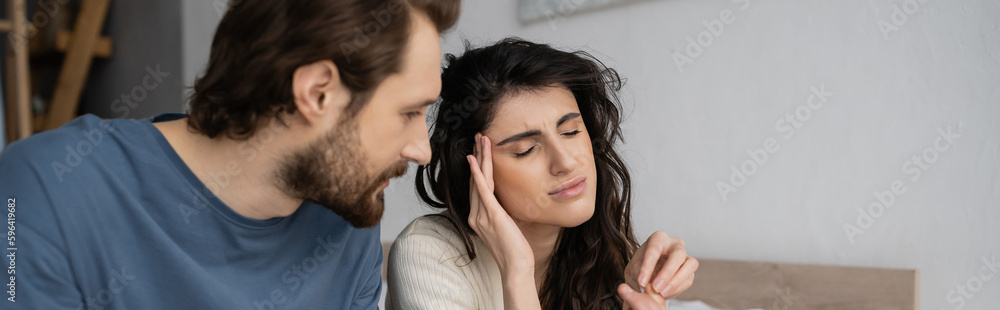 Woman with headache taking pill from caring boyfriend at home, banner. Woman with headache taking pill from caring boyfriend at home, banner.