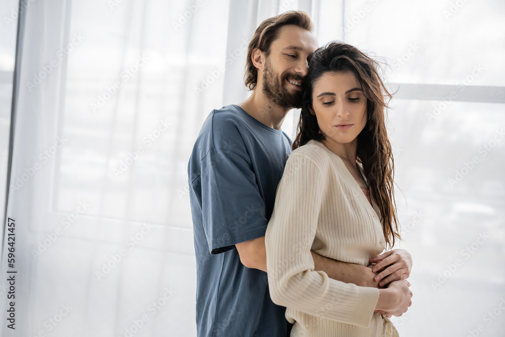 Cheerful man closing eyes while embracing brunette girlfriend at home. Cheerful man closing eyes while embracing brunette girlfriend at home.