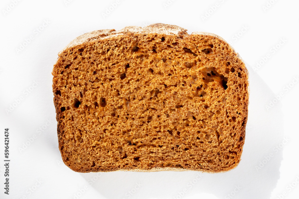 Slice of fresh delicious dark bread on white background in sunlight close up Slice of fresh delicious dark bread on white background in sunlight close up