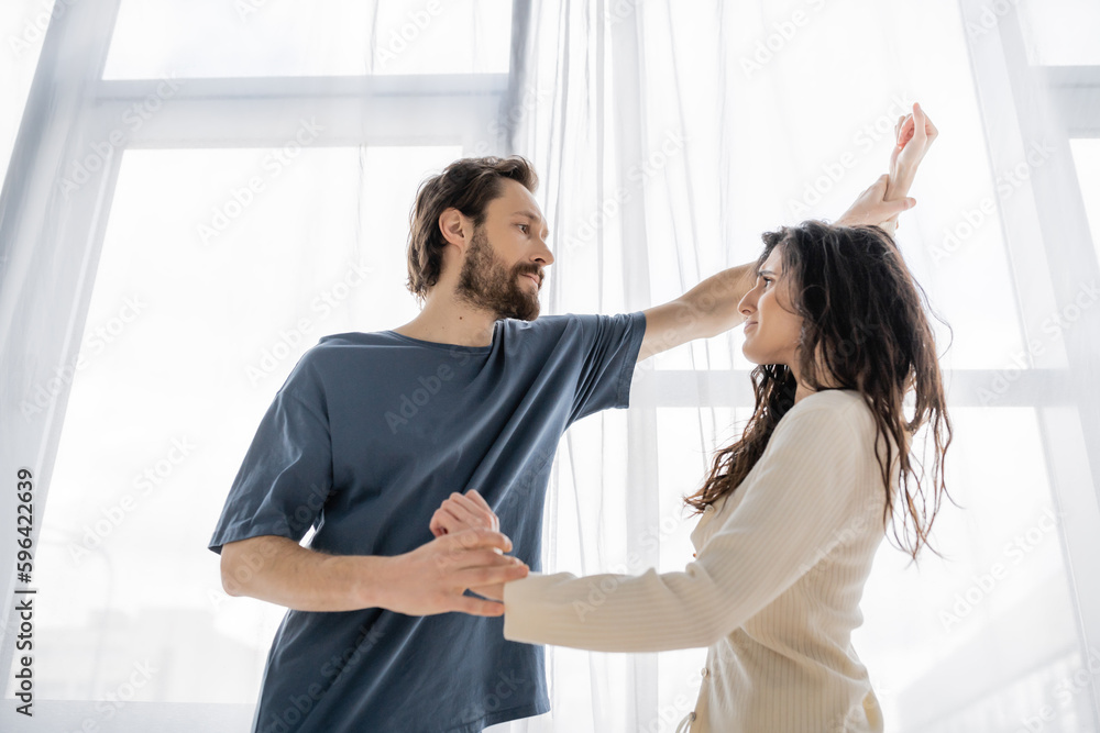 Low angle view of angry man holding hands of scared girlfriend at home. Low angle view of angry man holding hands of scared girlfriend at home.