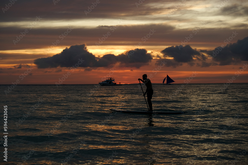 silhouette of a man on the sup board against the backdrop of sunset