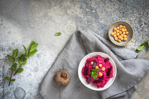 Bowl with beetroot hummus on a rustic grey background, top view, copy space
