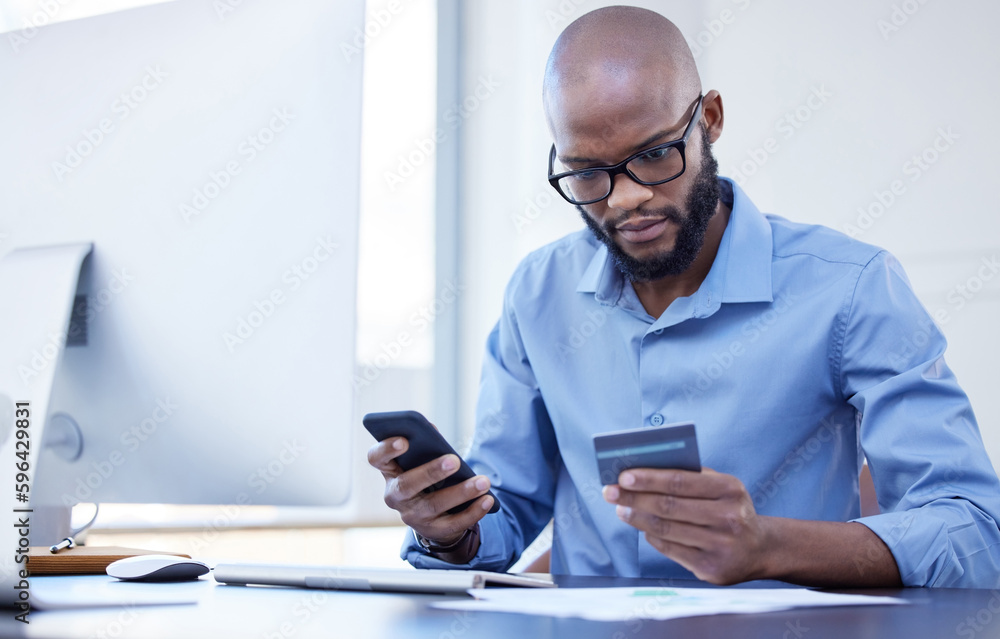 Technology helps make my life easier. Shot of a young businessman using a credit card and phone in an office at work. Technology helps make my life easier. Shot of a young businessman using a credit card and phone in an office at work.