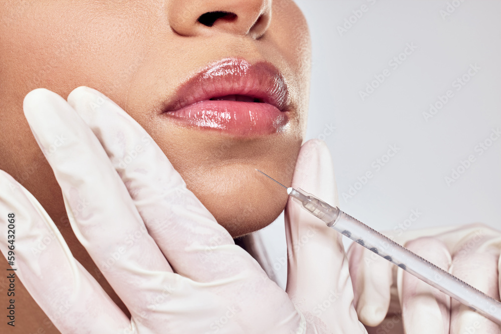 One syringe for all your dreams. Shot of a woman having her chin injected with botox against a studio background. - obrazy, fototapety, plakaty 