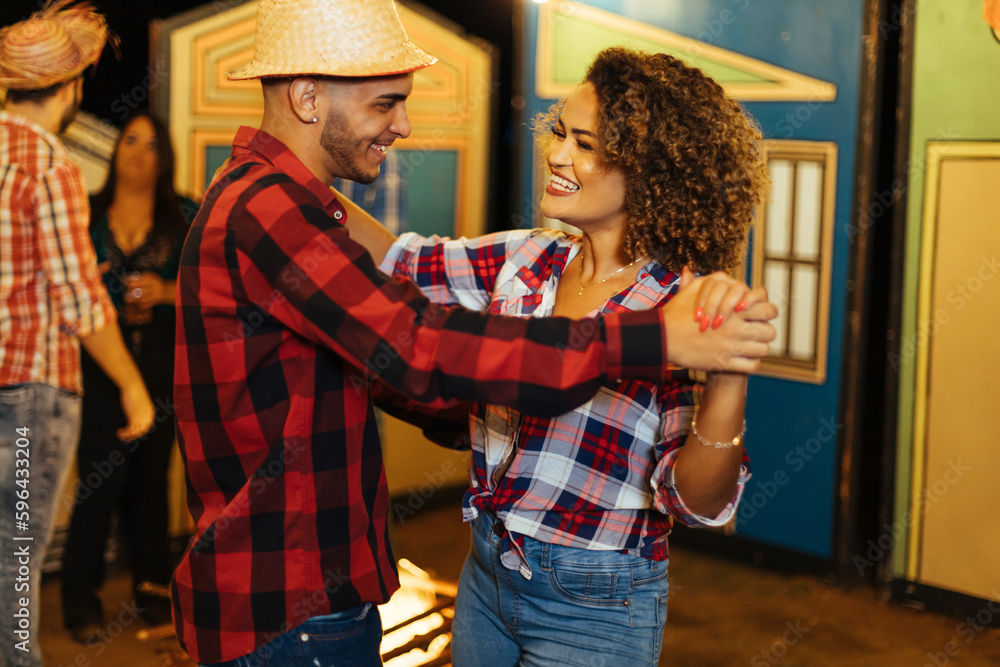 Obraz premium Brazilian couple wearing traditional clothes for Festa Junina - June festival - dancing under the night sky