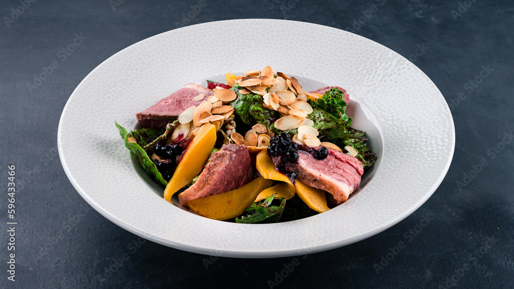 Fresh meat salad with beef slices, mango, beet leaves, berry jam and almond petals.