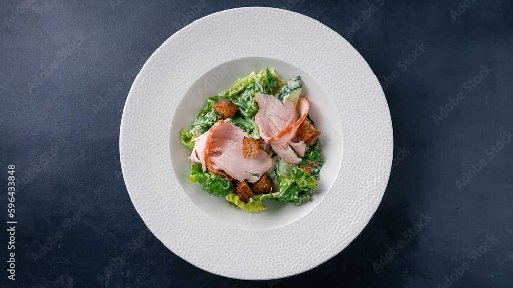 Salad with chicken ham, cucumber, lettuce, croutons and mayonnaise on a dark table. Salad with chicken ham, cucumber, lettuce, croutons and mayonnaise on a dark table.
