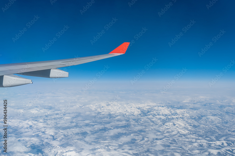 View from the airplane window. The wing of an aircraft during a flight in daylight at high altitude. View from the airplane window. The wing of an aircraft during a flight in daylight at high altitude.