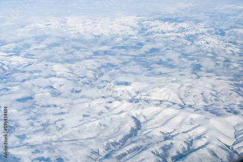 Aerial view of the Siberian hills and mountains covered with snow in the tundra. Siberia  Far East of Russia. Snow-covered tundra in the Arctic.