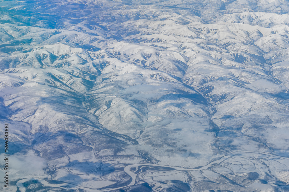 Fototapeta premium Aerial view of the Siberian hills and mountains covered with snow in the tundra. Siberia, Far East of Russia. Snow-covered tundra in the Arctic.