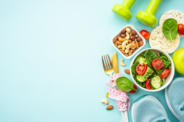 Healthy lifestyle, diet and losing weight background. Sport shoes, dumbell and healthy food with measuring tap on blue. Flat lay with copy space.