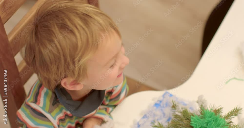 Child plays with cotton wool while sitting at the table. He applies the material to the face, makes the beard imitation. Fooling around in class, positive mood motivation. Child plays with cotton wool while sitting at the table. He applies the material to the face, makes the beard imitation. Fooling around in class, positive mood motivation.