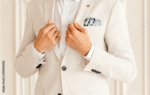 Hands of the groom in a white jacket on a white background. 