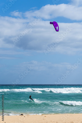 Kitesurfing. Unrecognizable man is flying on the sea wave on the board