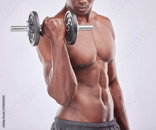 This is how I built a body of steel. Studio shot of a muscular young man exercising with a dumbbell against a grey background.