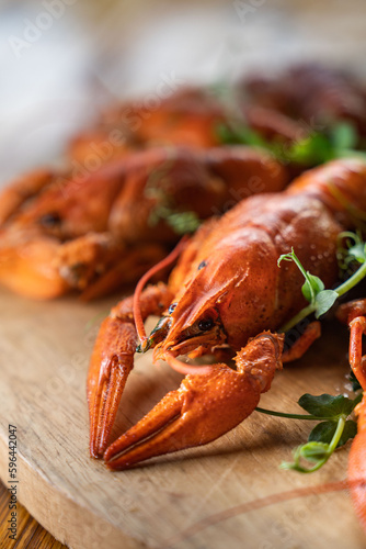 Boiled crayfish with lemon, dill and herbs on a wooden cutting board on blue wooden background. Crayfish dish