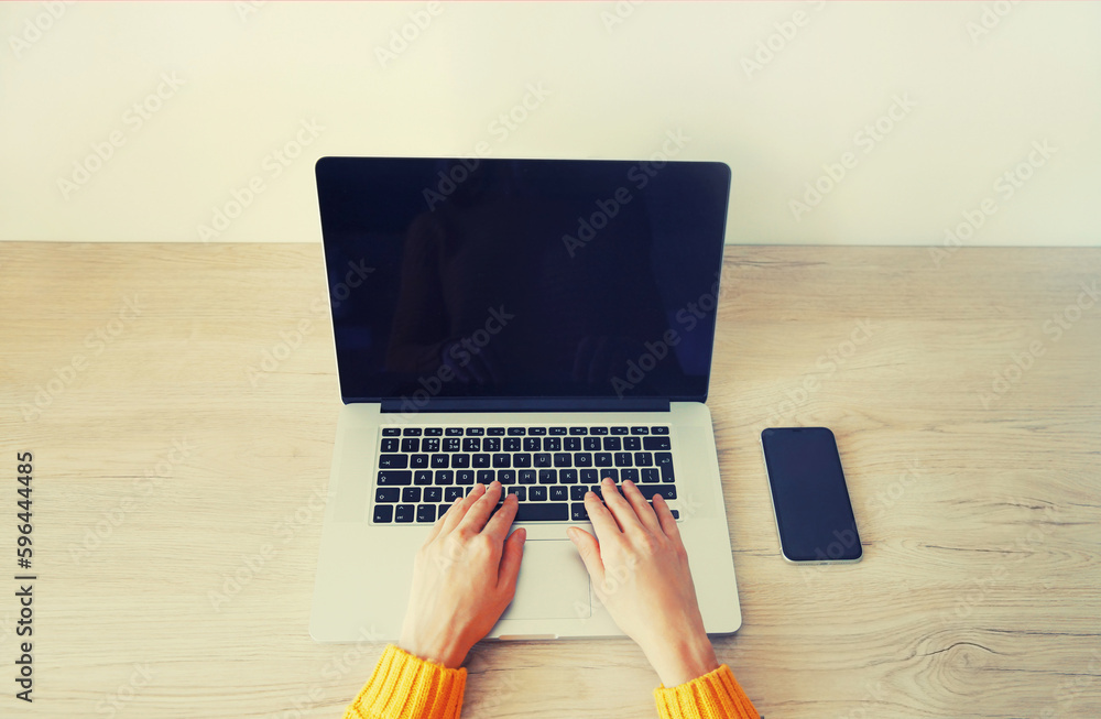 Close up woman working with laptop using smartphone on her desk in the room at home, blank black screen devices Close up woman working with laptop using smartphone on her desk in the room at home, blank black screen devices