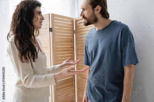 Side view of brunette woman talking to angry boyfriend at home.