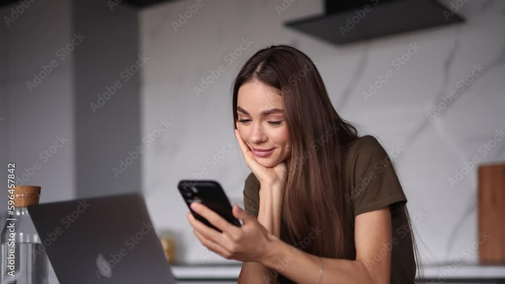 Young woman dreaming after using phone in the kitchen Young woman dreaming after using phone in the kitchen