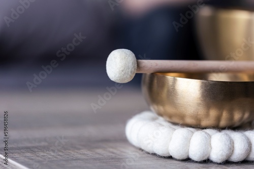 A close up of a tibetan singing bowl or himalayan bowl, with a mallet lying on top of it to make a relaxing sound. The object is used for meditation, relaxation and therapy to relieve stress.