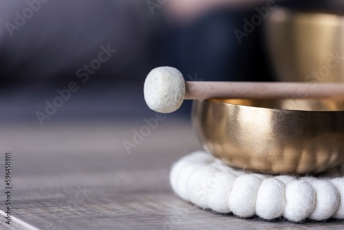 A portrait of a tibetan singing bowl or himalayan bowl, with a mallet lying on top of it to make a relaxing sound. The object is used for meditation, relaxation and therapy to relieve stress.