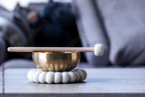 A portrait of a himalayan bowl or tibetan singing bowl, with a mallet lying on top of it to make a relaxing sound. The object is used for therapy to relieve stress and meditation, relaxation.