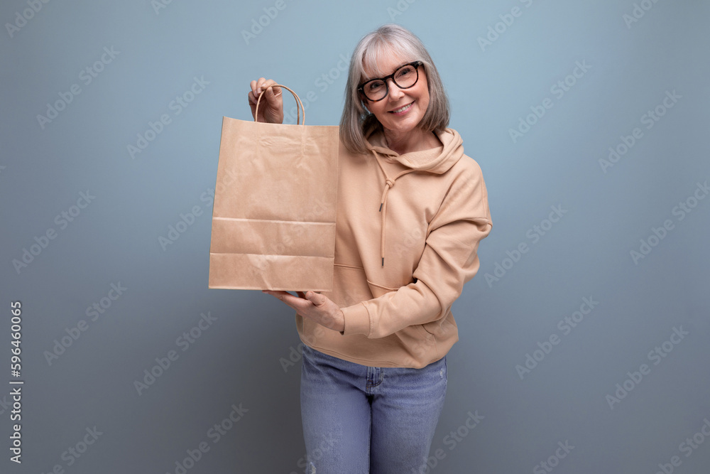 middle aged business woman with gray hair holding a package for retirement insurance on a studio background with copy space middle aged business woman with gray hair holding a package for retirement insurance on a studio background with copy space