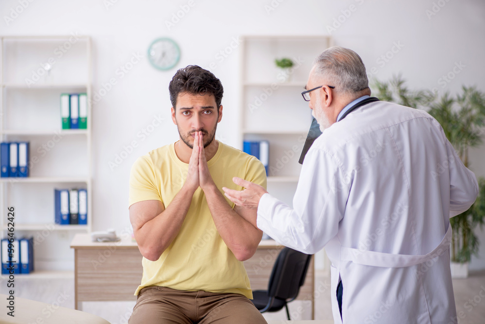 Obraz premium Young male patient visiting old male doctor