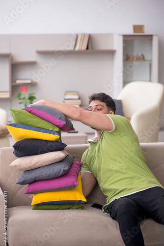 Young man with a lot of pillows sitting on the sofa © Elnur