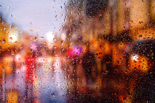 City view through a window on a rainy night,Rain drops on window with road light bokeh, City life in night in rainy season abstract background. Focus on drops on glass	
