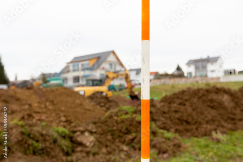 orange and white boning rod for surveying in the foreground of a construction site in a new development area that is blurred in the background photo