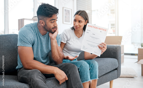 I thought you paid the rent. Shot of a young couple sitting on the sofa at home and feeling stressed after receiving an eviction notice. photo